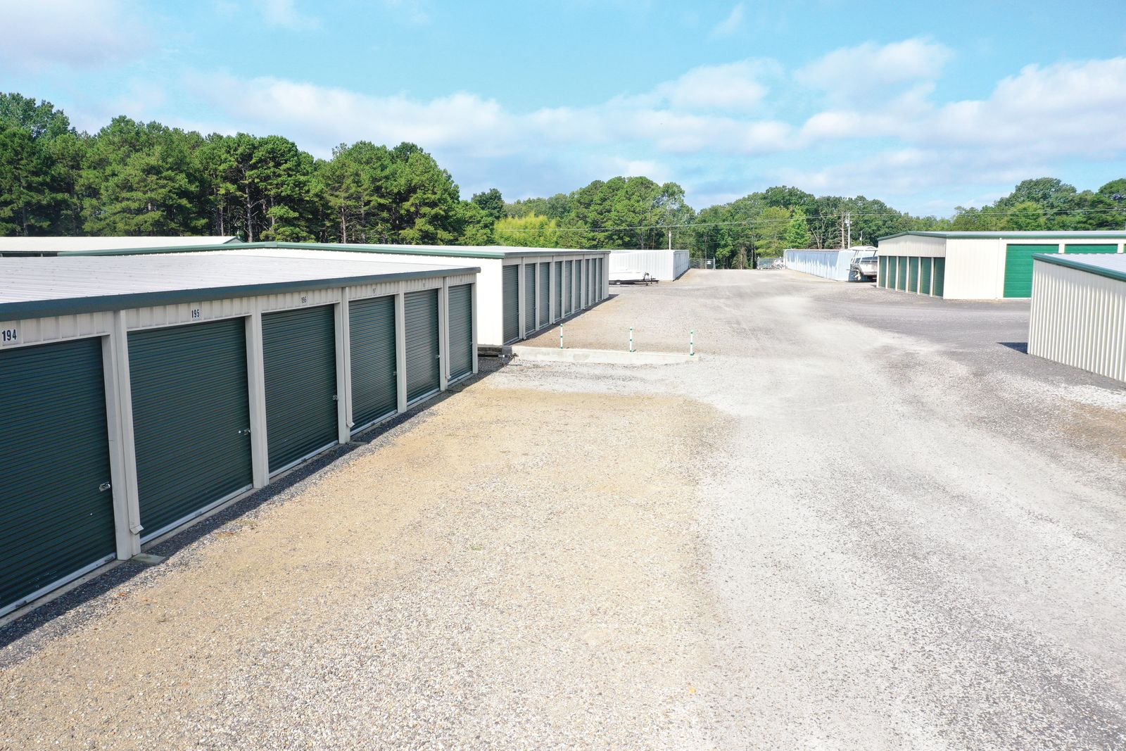 Drive-up storage unit aisle with green roll-up doors at Golden Anchor Storage